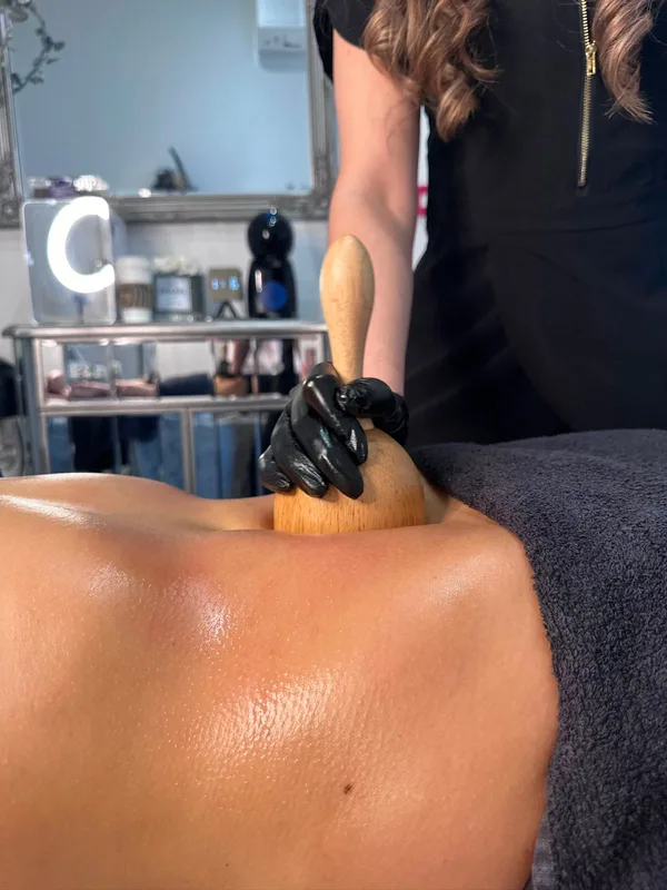 Wood therapy massage being performed across a client's back and shoulders