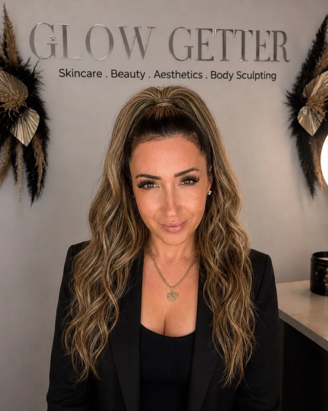Sabrina, founder of Glow Getter Bedford, in the studio beneath the Glow Getter sign